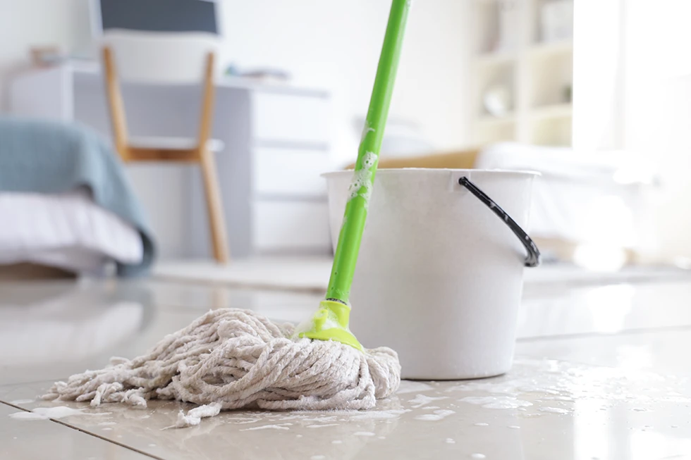 Nasser Mopp mit Eimer auf dem Boden im Studentenwohnheim, Nahaufnahme